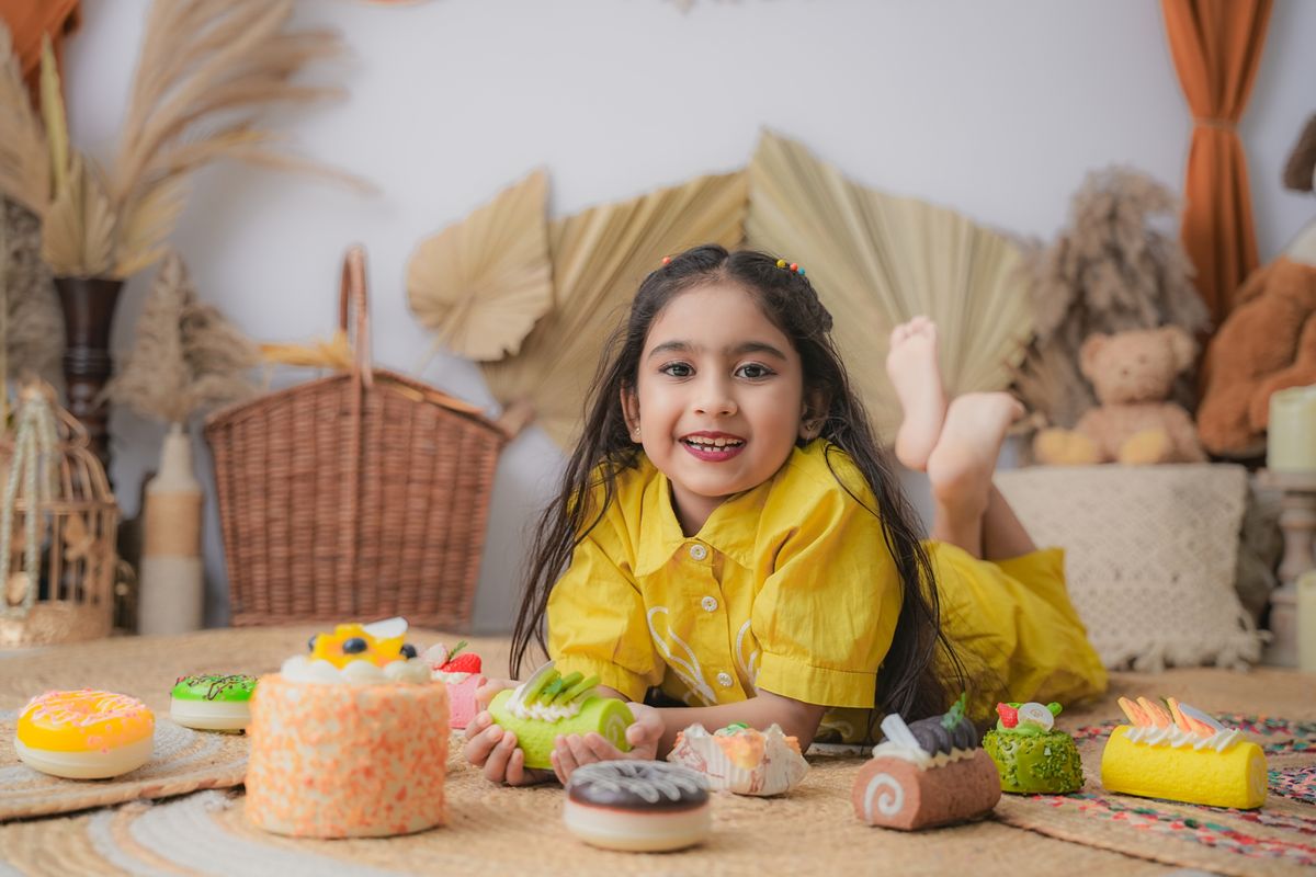 Happy kid surrounded by cake-shaped toys